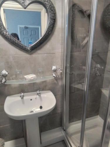 a bathroom with a sink and a shower with a mirror at Sherwood Lodge in Skegness