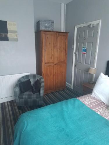 a bedroom with a bed and a chair and a cabinet at Sherwood Lodge in Skegness