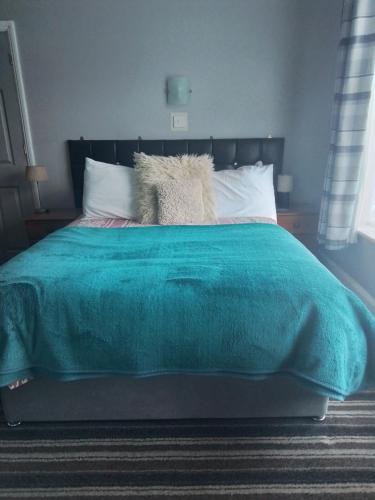 a bed with a green blanket and white pillows at Sherwood Lodge in Skegness