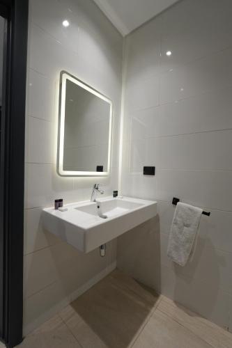 a white bathroom with a sink and a mirror at NewCity Hotel & Suites in Cairo