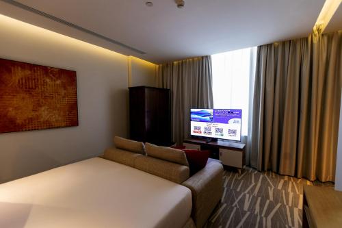 a living room with a couch and a flat screen tv at Ramada Hotel & Suites by Wyndham Al Qassim in Al Bukayriyah