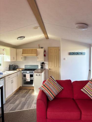 a living room with a red couch in a kitchen at Family-Friendly 3-Bed Caravan Recently Renovated on Seven Bays Holiday Park, Padstow in Saint Merryn