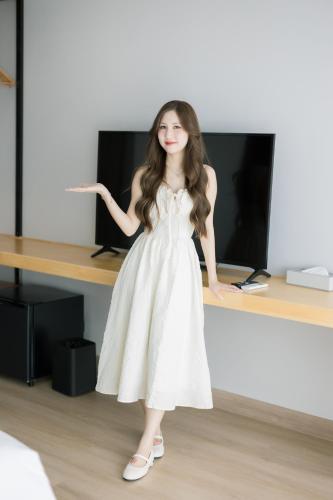 a young girl in a white dress standing in front of a desk at The Horizon Groove Hotel in Ban Khlong