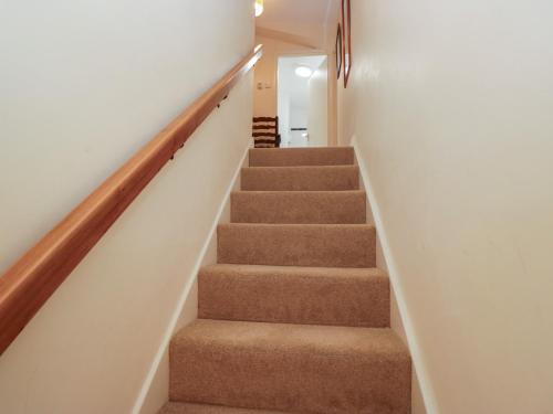 a staircase in a house with brown carpet at The Old Kitchen in Grange Over Sands