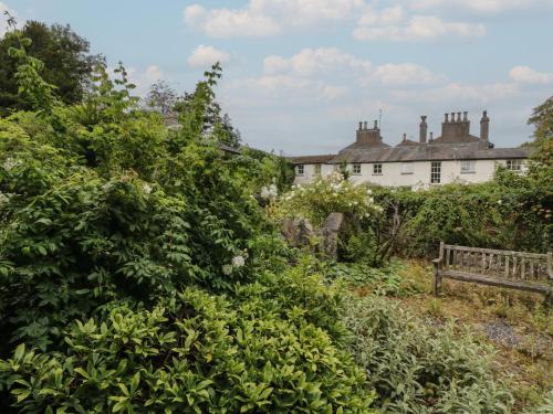 a garden with a bench in front of a house at The Old Kitchen in Grange Over Sands