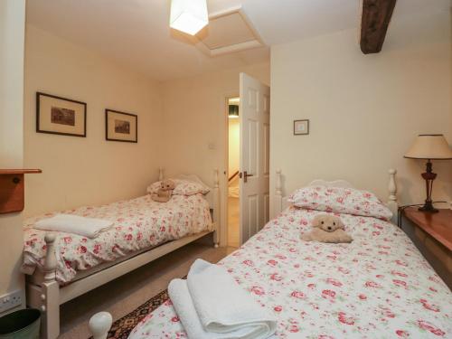 a bedroom with two beds and a teddy bear on the bed at Huntsman's Cottage in Grange Over Sands