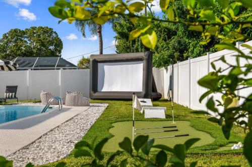 a backyard with a pool and a large screen next to a fence at The Beverley Pool Hot Tub Near Clearwater Beach in Clearwater