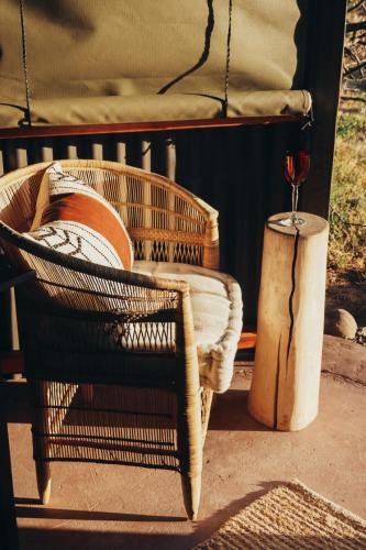 einen Rattansessel und ein Glas Wein auf einem Stumpf in der Unterkunft The Karoo Glamping Dome in Graaff-Reinet