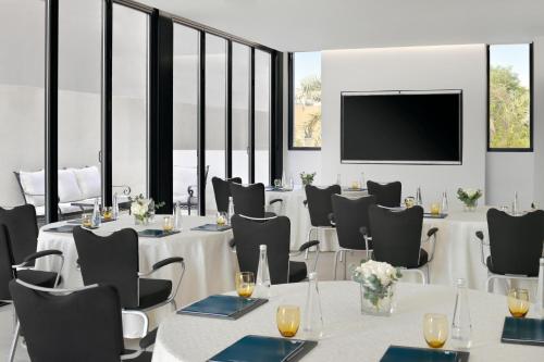 a conference room with tables and chairs and a flat screen tv at JA The Manor Hotel, Dubai in Dubai