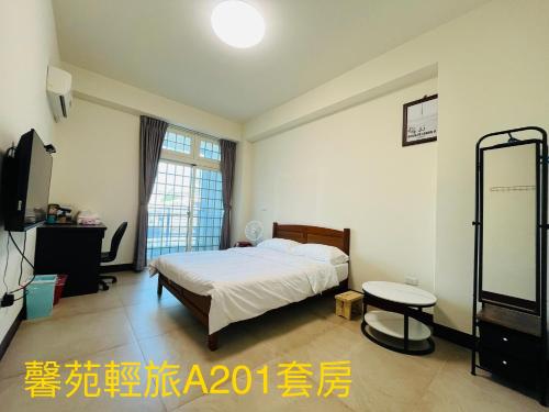 a bedroom with a bed and a table and a tv at Xinyuan Guest House in Beidou