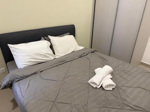 a bed with two white towels on top of it at Shelisa's Modern 3BR House at Suria Garden Puchong in Puchong