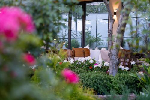 a table and chairs in a garden with pink flowers at REDROOF country house hotel in Goris