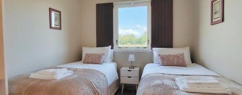 two beds in a room with a window at Orchard Cottages at Gorton House in Roslin