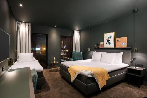 a hotel room with two beds and a chair at Van der Valk Hotel Amsterdam - Amstel in Amsterdam