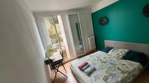 セットにあるAppartement confortable avec vueの緑の壁のベッドルーム1室、窓付きのベッド1台が備わります。