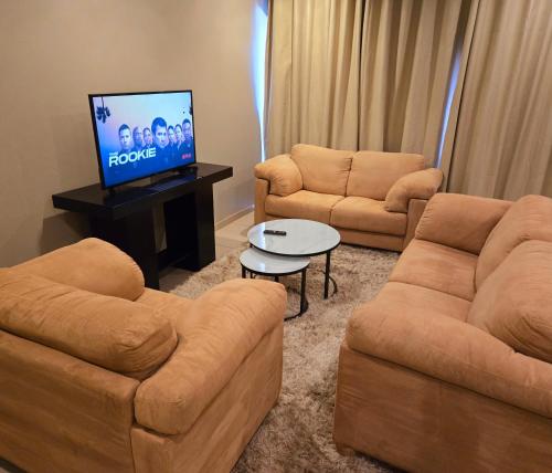 a living room with two couches and a flat screen tv at Sandown Suites and Conference Centre in Johannesburg