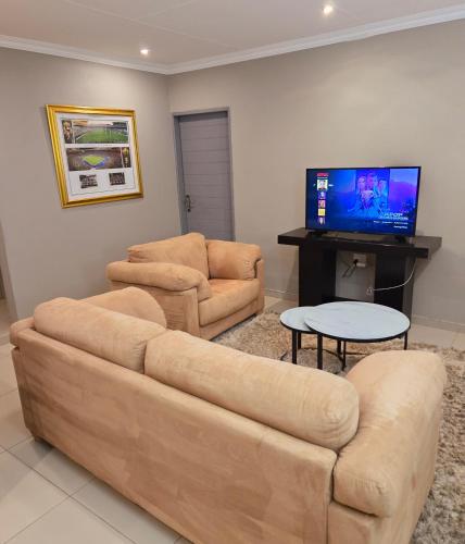 a living room with two couches and a flat screen tv at Sandown Suites and Conference Centre in Johannesburg