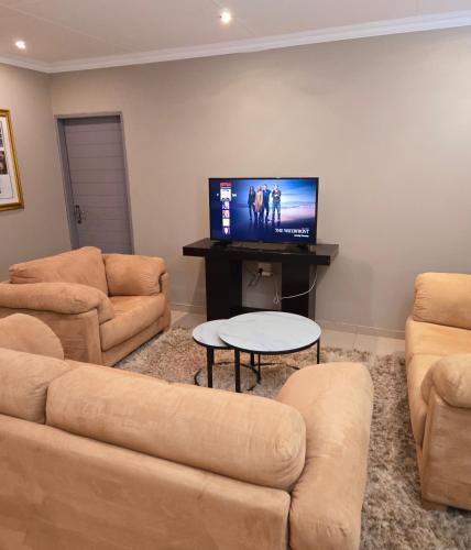 a living room with couches and a flat screen tv at Sandown Suites and Conference Centre in Johannesburg