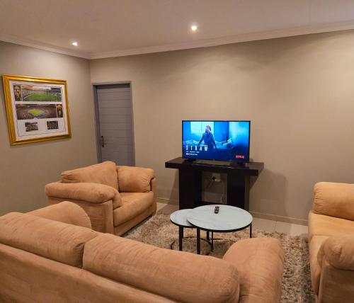a living room with couches and a flat screen tv at Sandown Suites and Conference Centre in Johannesburg