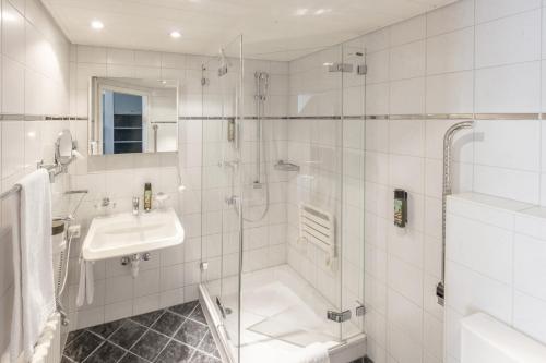 a white bathroom with a shower and a sink at Hotel und Restaurant zum goldenen Kopf in Bülach