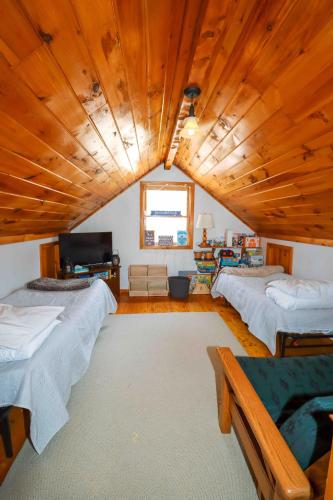 a large room with three beds and a large wooden ceiling at Lake Christopher Cabin in Bryant Pond