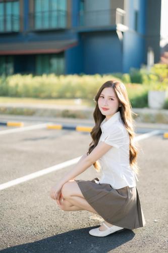 a woman in a skirt kneeling on the street at The Horizon Groove Hotel in Ban Khlong