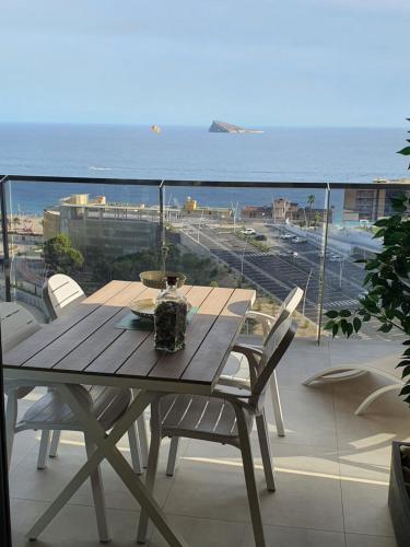a wooden table on a balcony with a view of the ocean at Sunset Waves Benidorm by KalmaRent in Benidorm