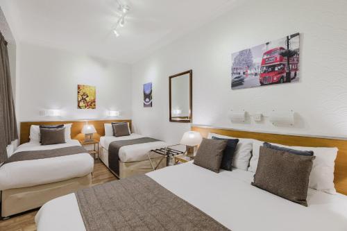 Una habitación de hotel con dos camas y un autobús rojo de dos pisos. en The Chapter Hotels - Falcon Hotel, en Londres