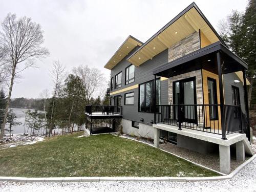 a house with a front porch and a balcony at Lakefront-Spa-Luxury in true nature! in La Minerve