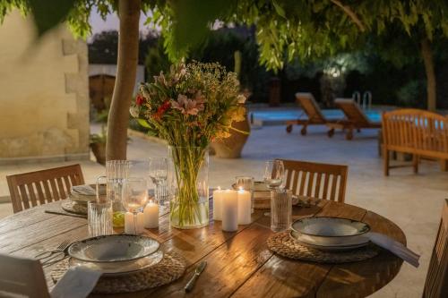 a wooden table with candles and flowers in a vase at Villa Petrohelidono in Petrokefálion
