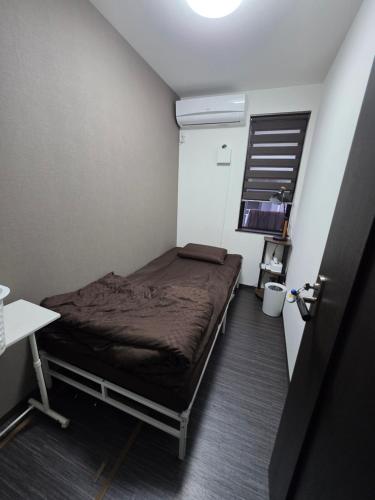 a small room with a bed and a television at NINN Guest House ニン ITM Airport 大阪空港 伊丹空港 in Ikeda
