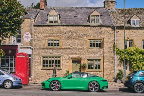 a green car parked in front of a brick building at Coniston House - Eco Hot Tub in Stow on the Wold