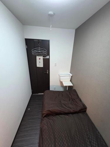 a small room with a bed and a door at NINN Guest House ニン ITM Airport 大阪空港 伊丹空港 in Ikeda