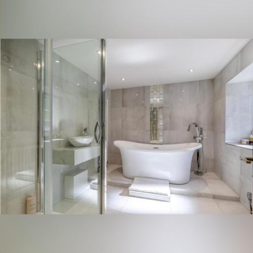 a white bathroom with a tub and a sink at Peak District Period Property near Chatsworth House in Bakewell