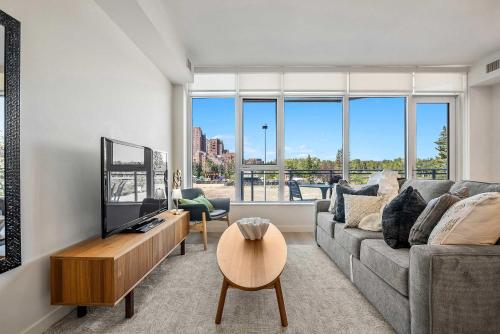 a living room with a couch and a tv at Riverside Retreat - Enjoy Walking Trails, FREE Banff Pass, Gym, Wine & Parking! Work Space Included! in Calgary