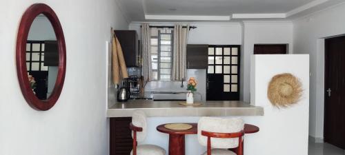 a kitchen with a counter with two stools and a mirror at Boho Comfort Homes in Diani Beach