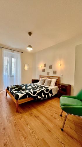 a bedroom with a bed and a green chair at Cobalto 2 Quartos Parque Cidade Pet Friendly in Aveiro