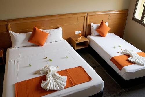 two beds in a room with orange and white at Hotel Golden Flora in Beni Mellal