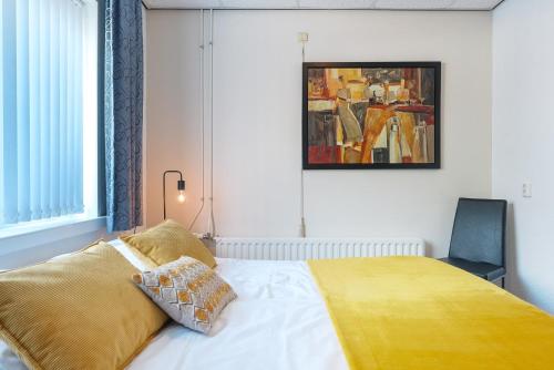 a bedroom with a bed with a yellow blanket on it at Hotel-Pension Ouddorp in Ouddorp