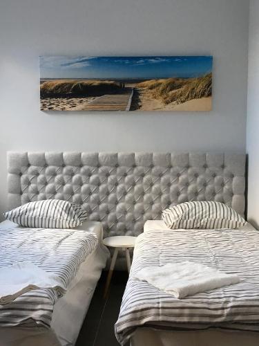 a bedroom with two beds and a painting on the wall at Panorama Gdynia Rooms in Gdynia