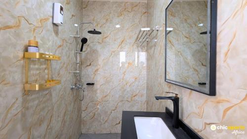 a bathroom with a sink and a shower with a mirror at Chic studio with parking and rooftop in Yaoundé