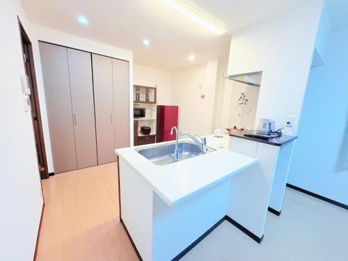 a white kitchen with a sink in a room at 褚之屋2号 in Fukuoka