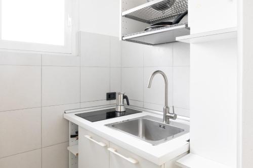 a white kitchen with a sink and a window at Vivace Bilocale con vista sul Naviglio -Mirable PM in Milan