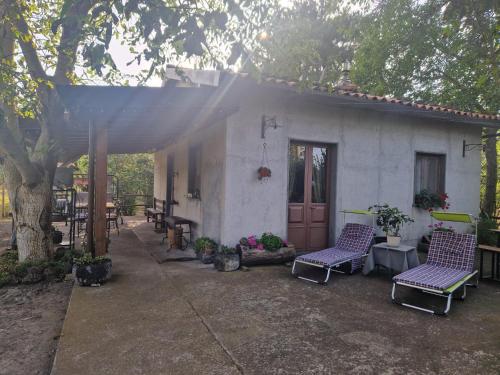 a house with two chairs and a table and a tree at La casa di Giulia in Bronte
