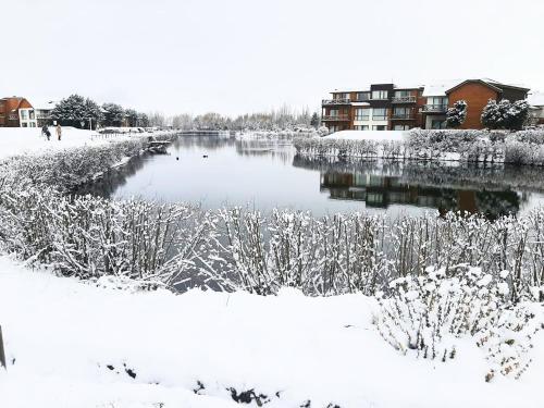 a river covered in snow with buildings in the background at Blue Aparts Dina Huapi Bariloche in Dina Huapi