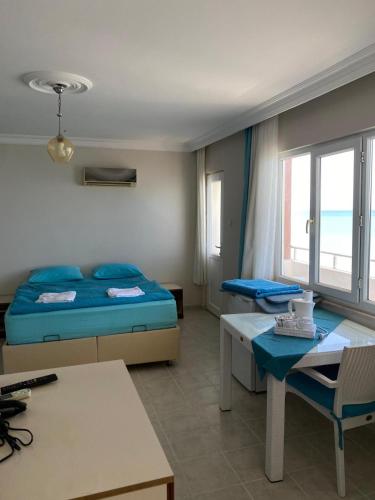a bedroom with a bed and a desk and a table at Abaş Masmavi Otel in Yumurtalık
