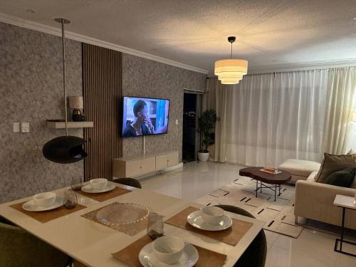 a living room with a table and a tv on the wall at 270 Degree City View Serenity in Windhoek