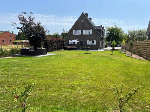 a large yard with a large house in the background at Maison François in Oostkamp