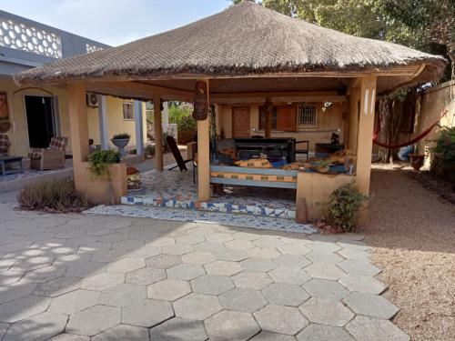 a gazebo with a straw roof on a patio at Chambre d'hôte Maryvonne & Mamadou in Nianing