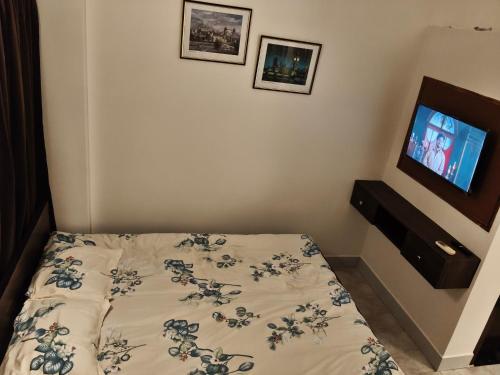a bedroom with a bed and a tv on the wall at Mimo's in Guwahati